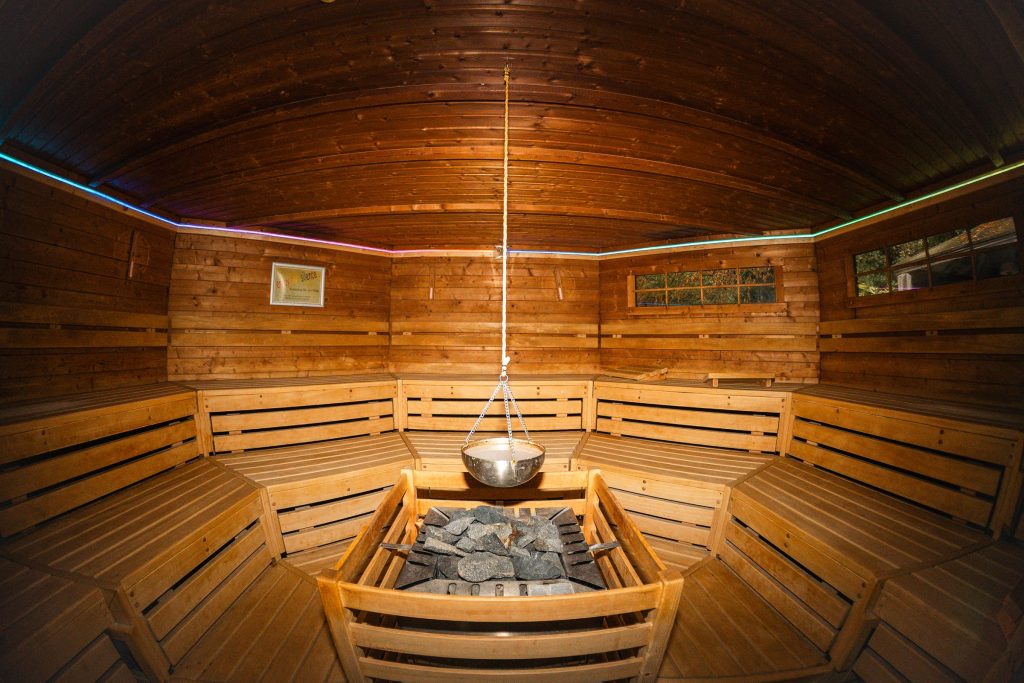 Biosauna mit Holzbänken rundum, in der Mitte der Saunaofen mit Steinen und darüber eine Schale